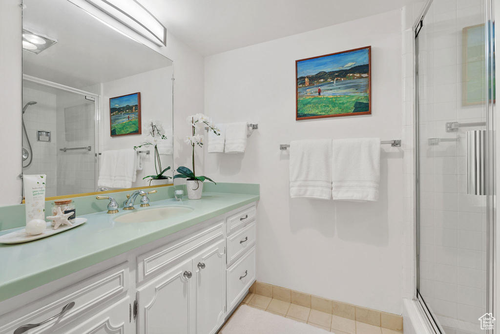 Full bathroom featuring vanity, a tile shower, and tile patterned floors