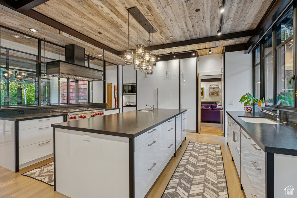 Kitchen with dark countertops, track lighting, modern cabinets, wooden ceiling, and white cabinets