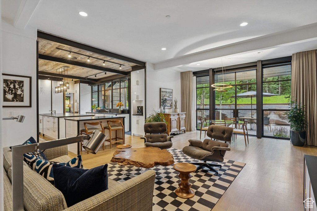 Living room with beam ceiling, light wood finished floors, recessed lighting, and a chandelier