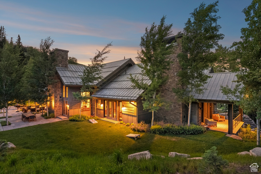 Rear view of property with a standing seam roof, a chimney, and a metal roof