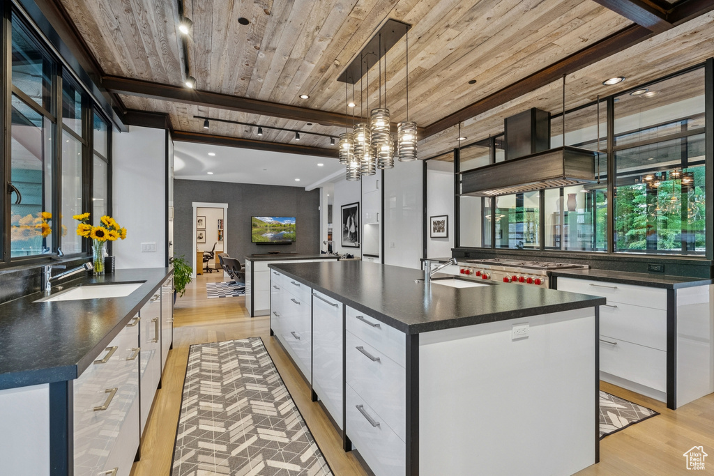 Kitchen featuring dark countertops, modern cabinets, light wood finished floors, white cabinetry, and a spacious island