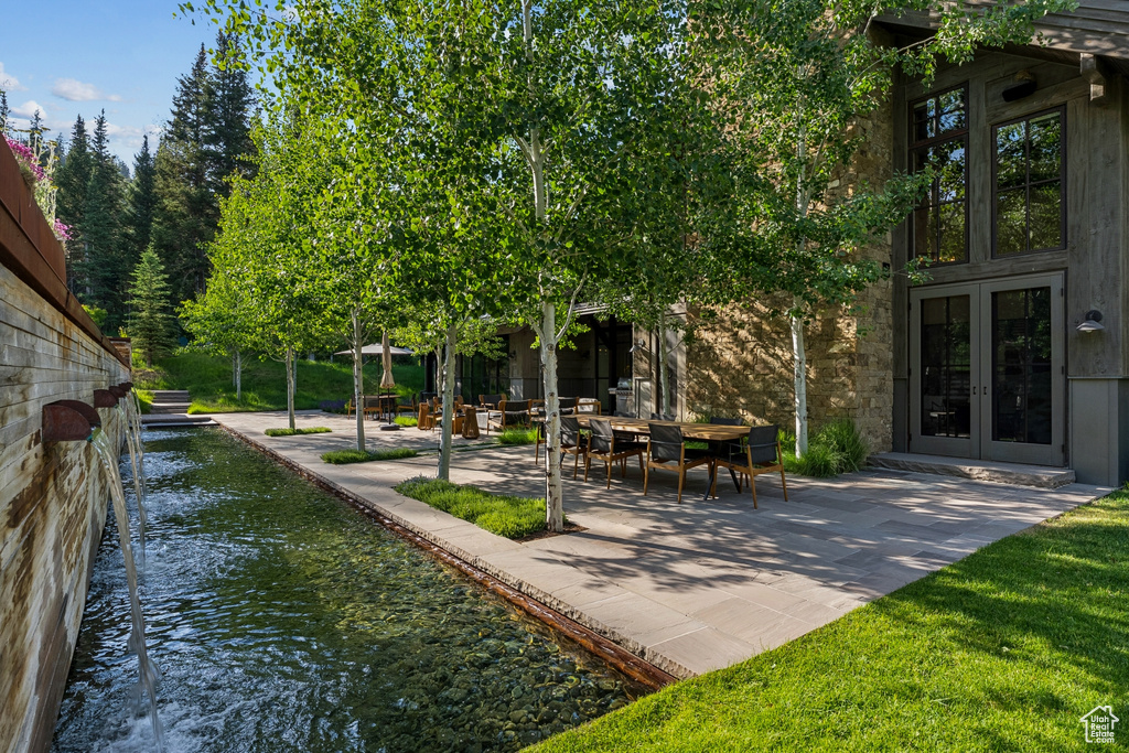 View of yard with french doors, a patio area, and a water view
