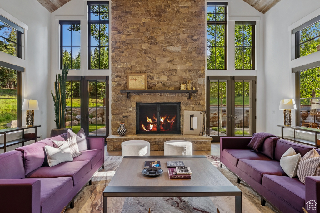 Living room featuring french doors, high vaulted ceiling, plenty of natural light, and a fireplace