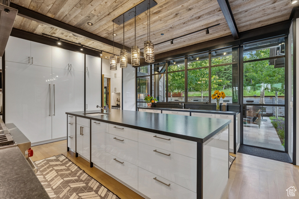 Kitchen featuring wooden ceiling, dark countertops, light wood finished floors, modern cabinets, and white cabinetry