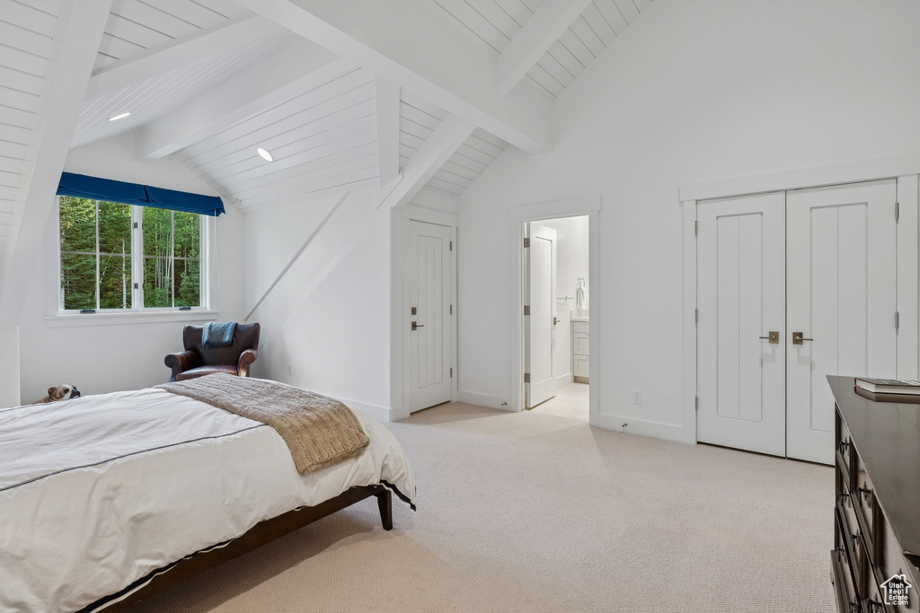 Bedroom with light colored carpet, wood ceiling, and ensuite bathroom
