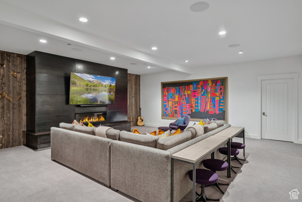 Living area featuring light colored carpet, recessed lighting, beam ceiling, and a glass covered fireplace