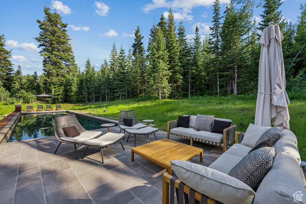 View of patio / terrace with an outdoor living space, a view of trees, and an outdoor pool