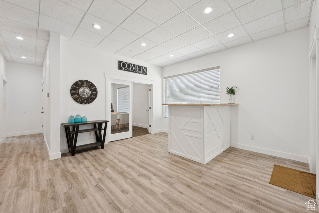 Empty room with light wood-type flooring, a drop ceiling, and recessed lighting