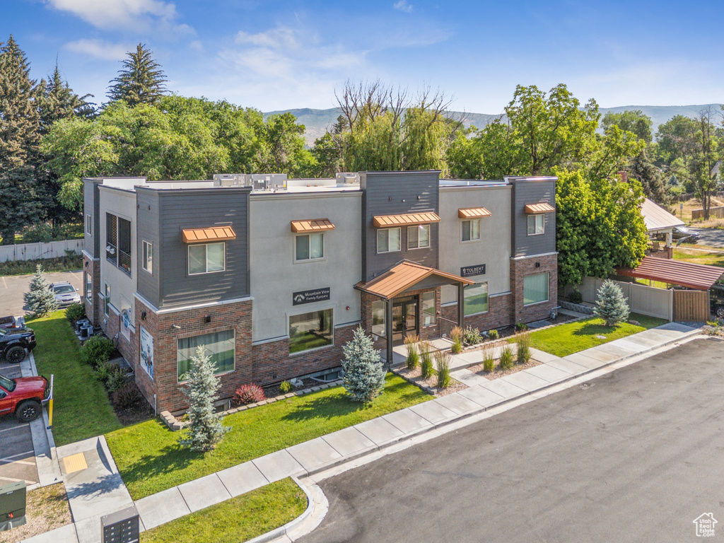View of front of home featuring a mountain view, stucco siding, and a front lawn