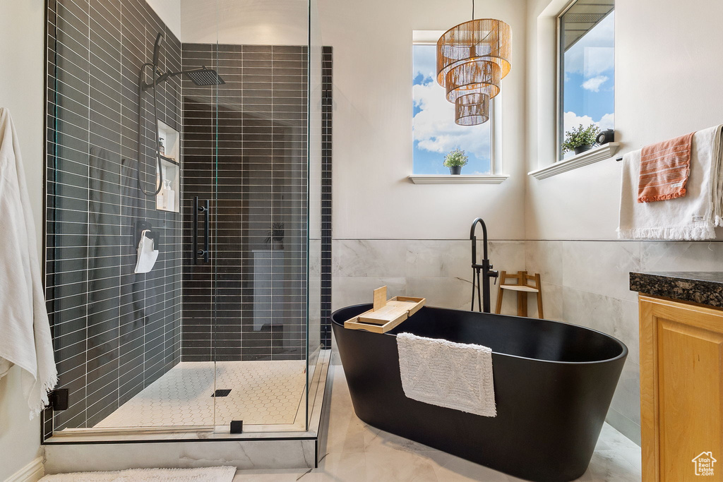 Full bathroom with tile walls, a shower stall, and a freestanding bath