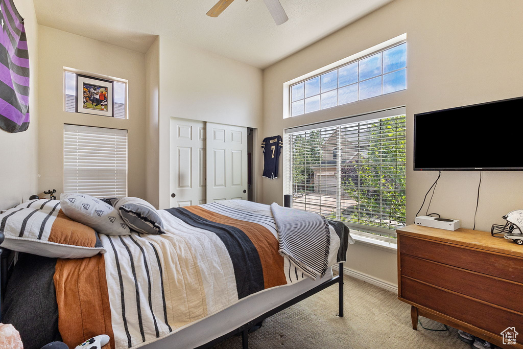 Bedroom featuring light colored carpet, ceiling fan, a closet, and a high ceiling