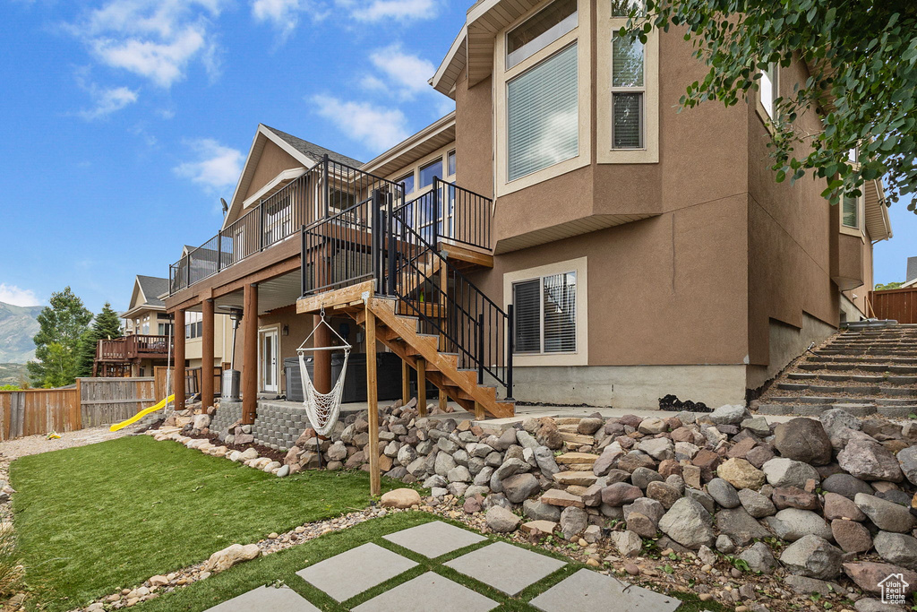 Rear view of property featuring stairs, a wooden deck, and stucco siding