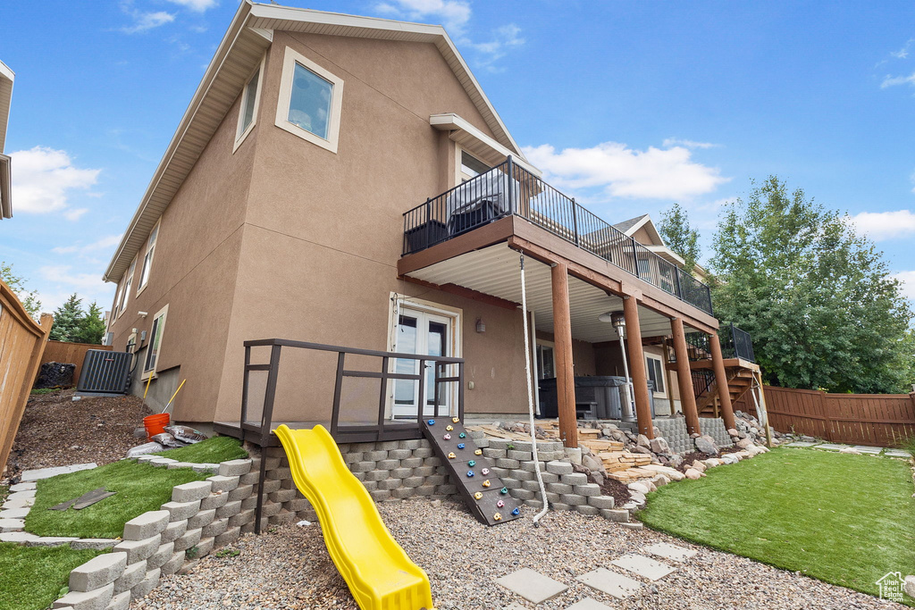 Rear view of house with a fenced backyard, stucco siding, and a playground