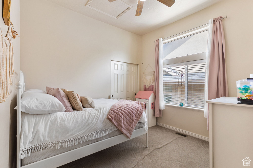 Carpeted bedroom featuring attic access, a closet, and ceiling fan