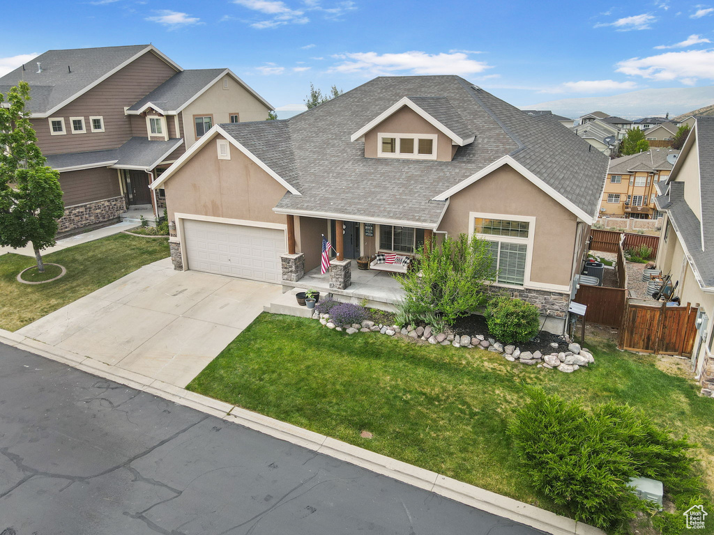 View of front of property featuring stone siding, roof with shingles, covered porch, and stucco siding