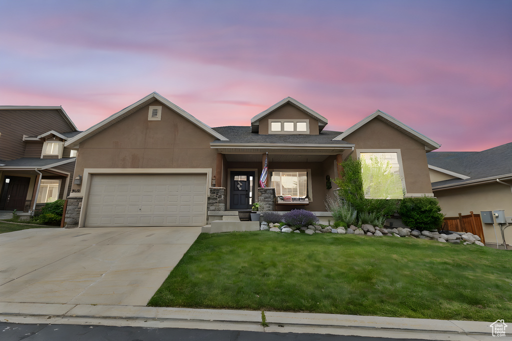 View of front of property featuring driveway, a lawn, a garage, and stucco siding