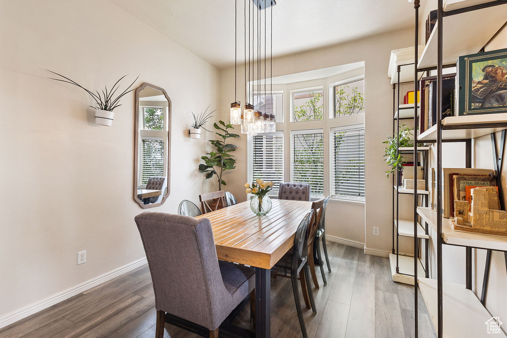 Dining space with healthy amount of natural light, a chandelier, and wood finished floors