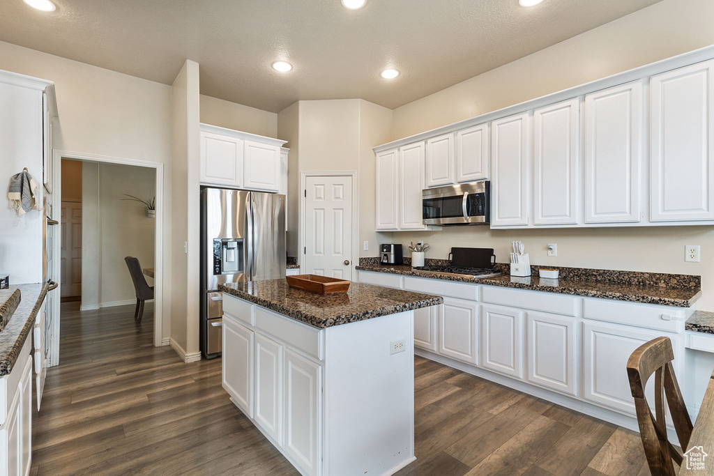 Kitchen with appliances with stainless steel finishes, white cabinets, a center island, dark wood finished floors, and recessed lighting