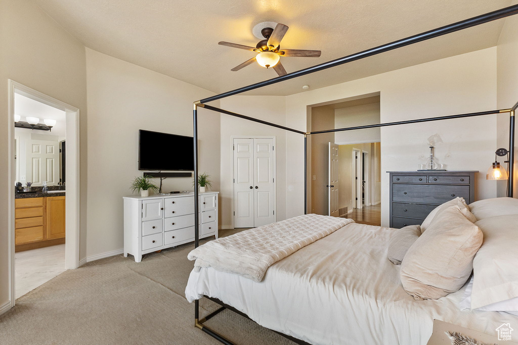 Bedroom with light carpet, ensuite bathroom, and ceiling fan