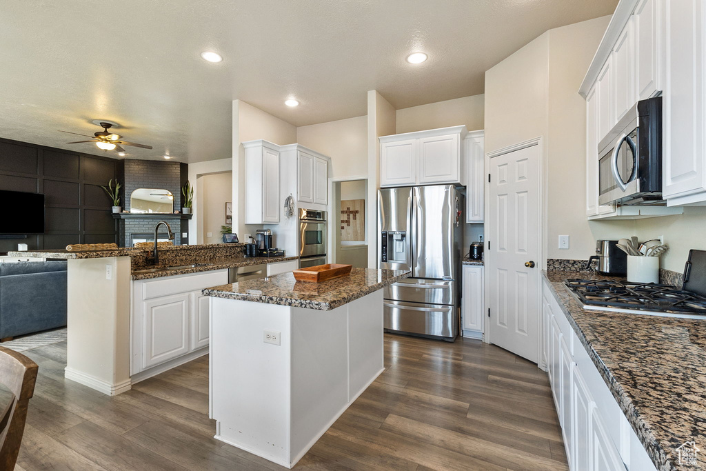 Kitchen with appliances with stainless steel finishes, open floor plan, ceiling fan, a peninsula, and white cabinets