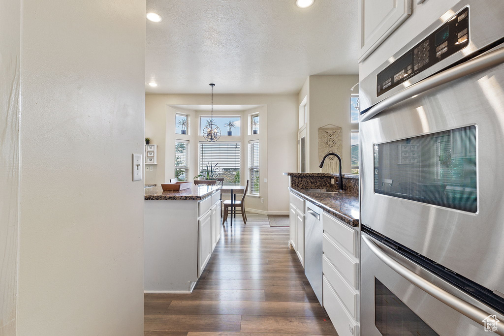 Kitchen featuring appliances with stainless steel finishes, dark wood finished floors, white cabinets, and recessed lighting