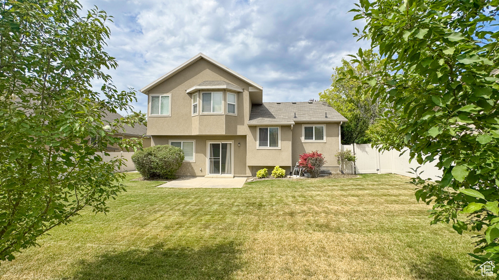 Rear view of property with stucco siding, a fenced backyard, and a patio