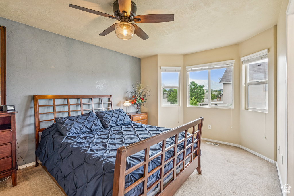 Carpeted bedroom featuring a ceiling fan and a textured ceiling