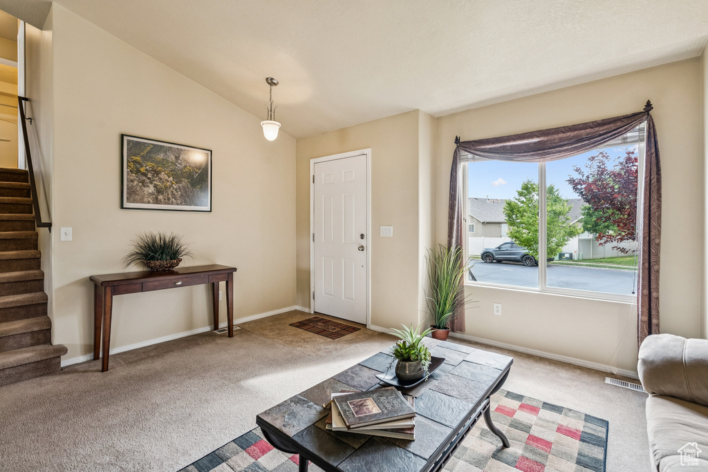 Carpeted entrance foyer featuring stairs and vaulted ceiling