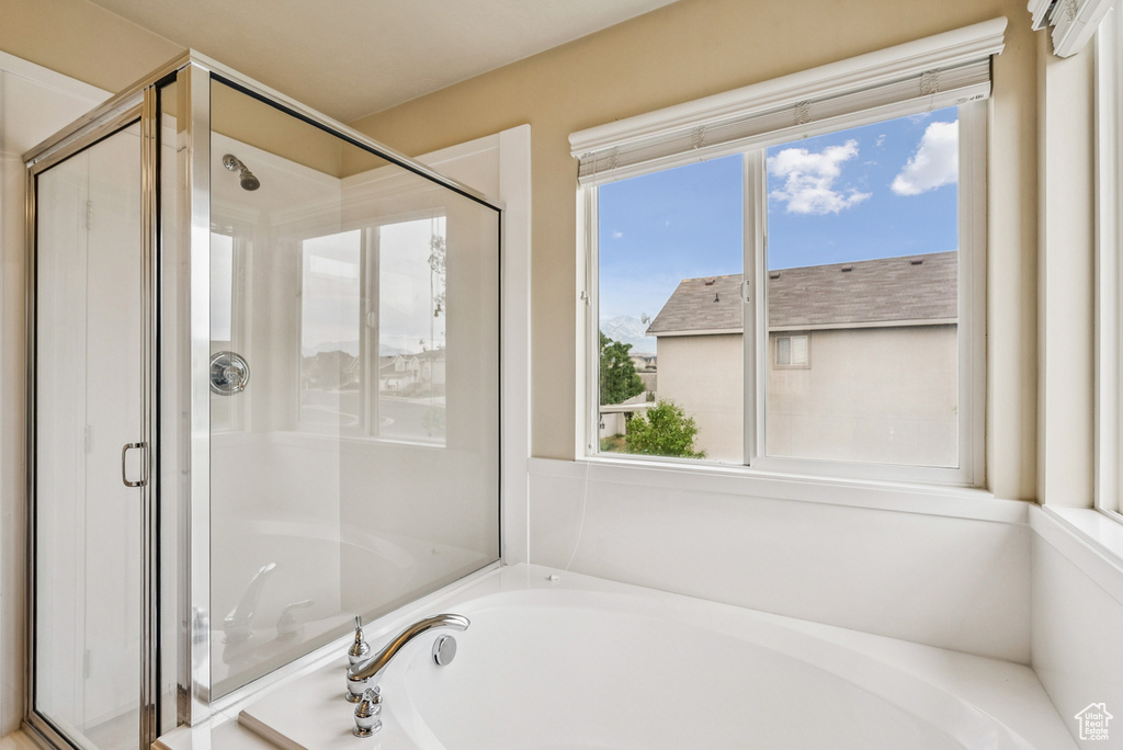 Bathroom featuring a garden tub, a stall shower, and healthy amount of natural light