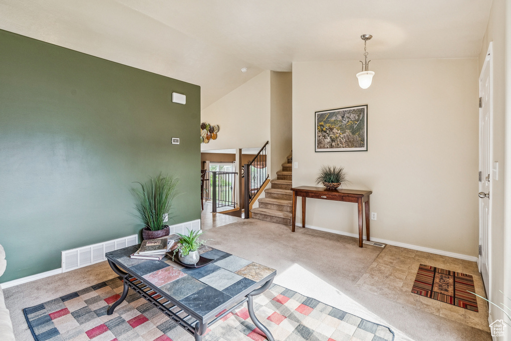 Carpeted entryway featuring stairway and high vaulted ceiling