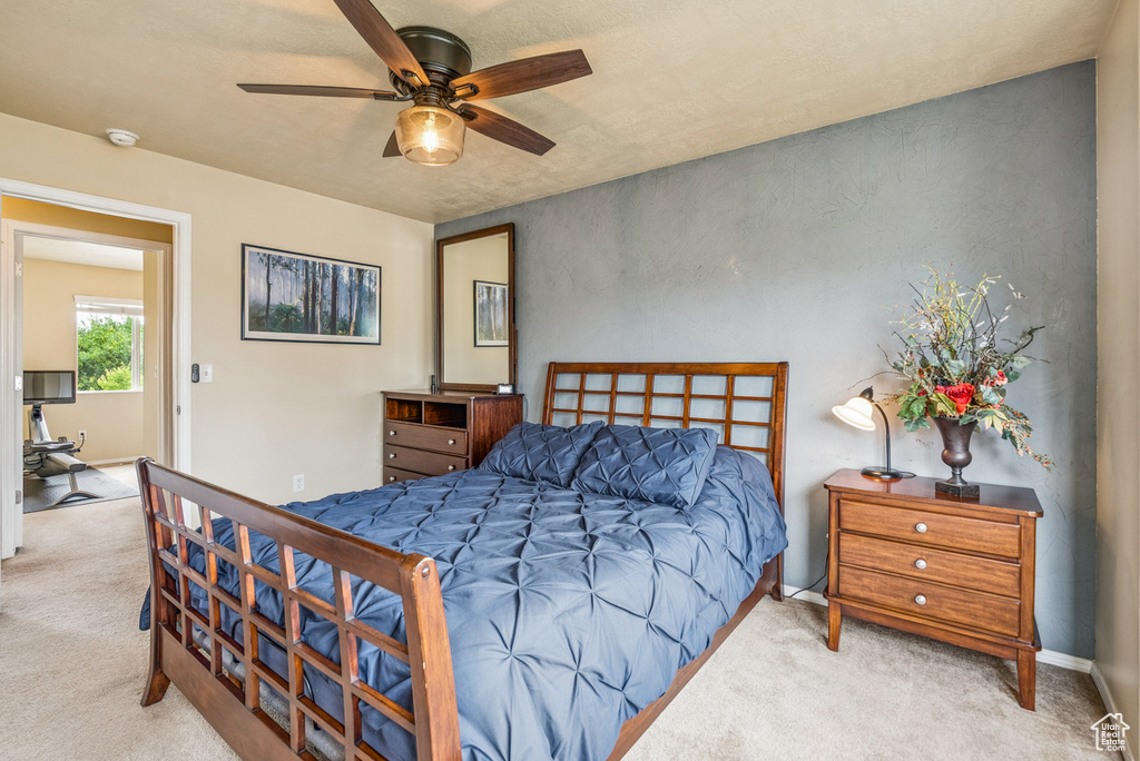 Carpeted bedroom with a ceiling fan and baseboards