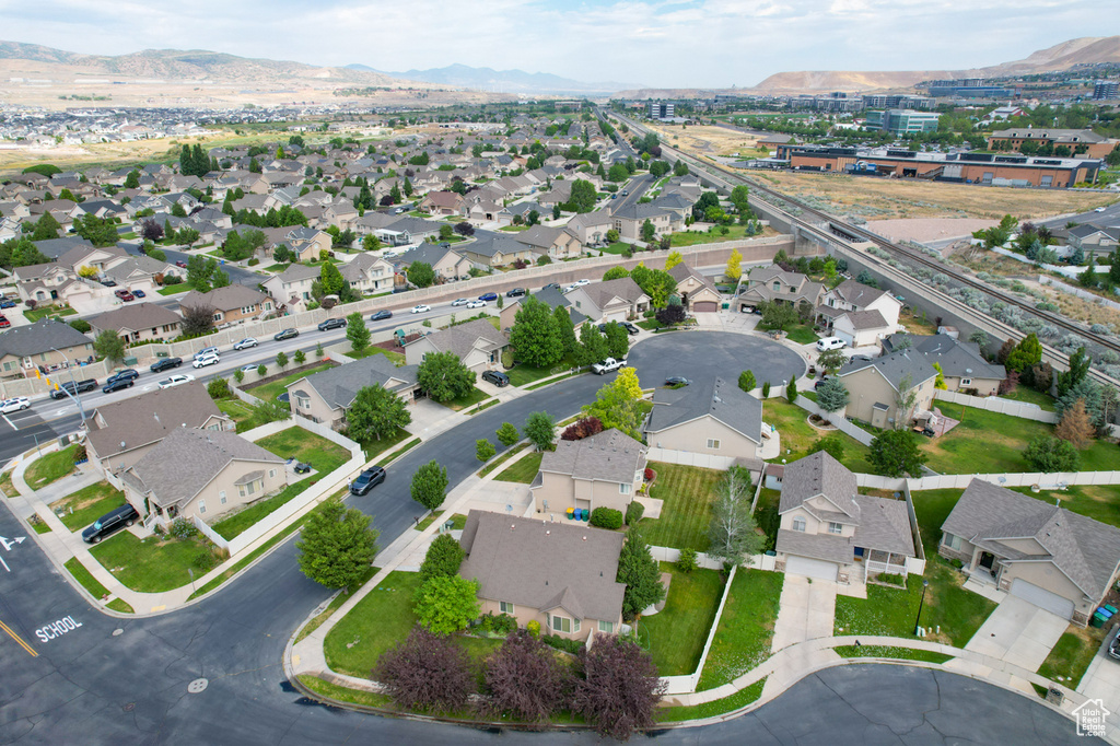 Aerial view of property and surrounding area featuring mountains and nearby suburban area