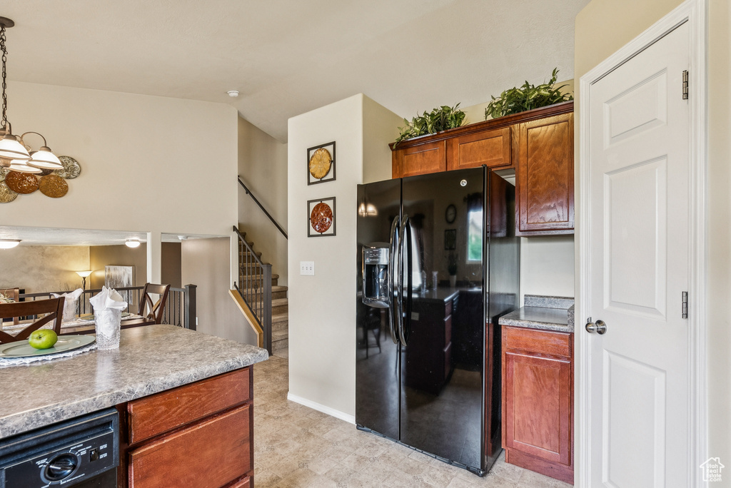 Kitchen featuring black fridge, a chandelier, brown cabinets, and decorative light fixtures
