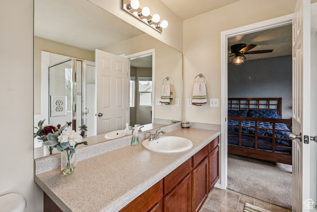 Bathroom with ensuite bathroom, vanity, ceiling fan, and a shower with shower door