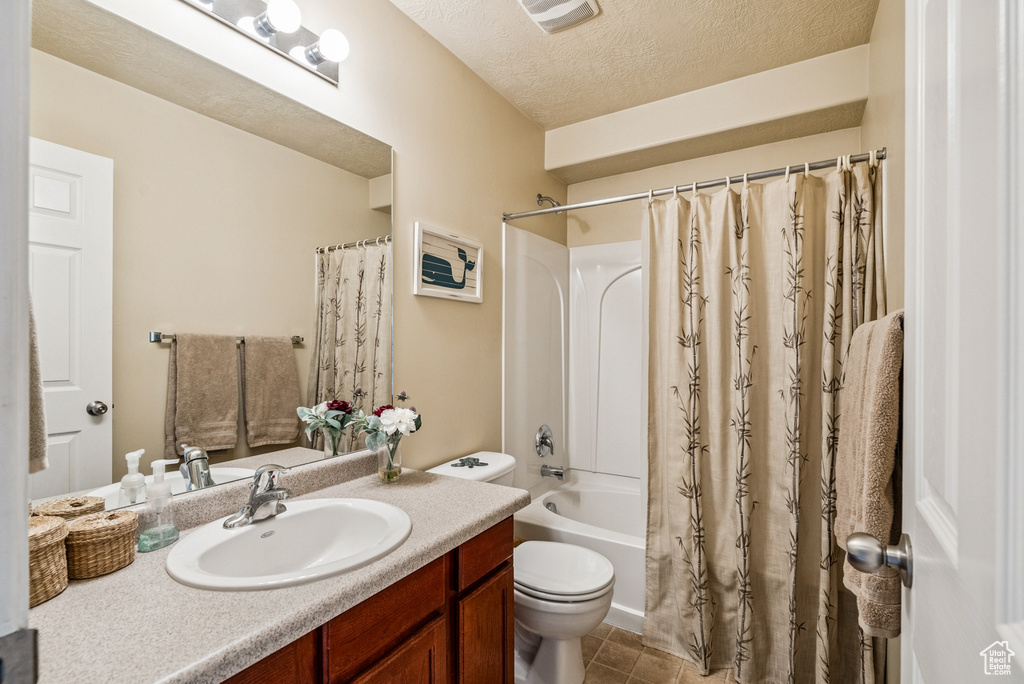 Full bathroom featuring vanity, shower / tub combo with curtain, a textured ceiling, and tile patterned floors