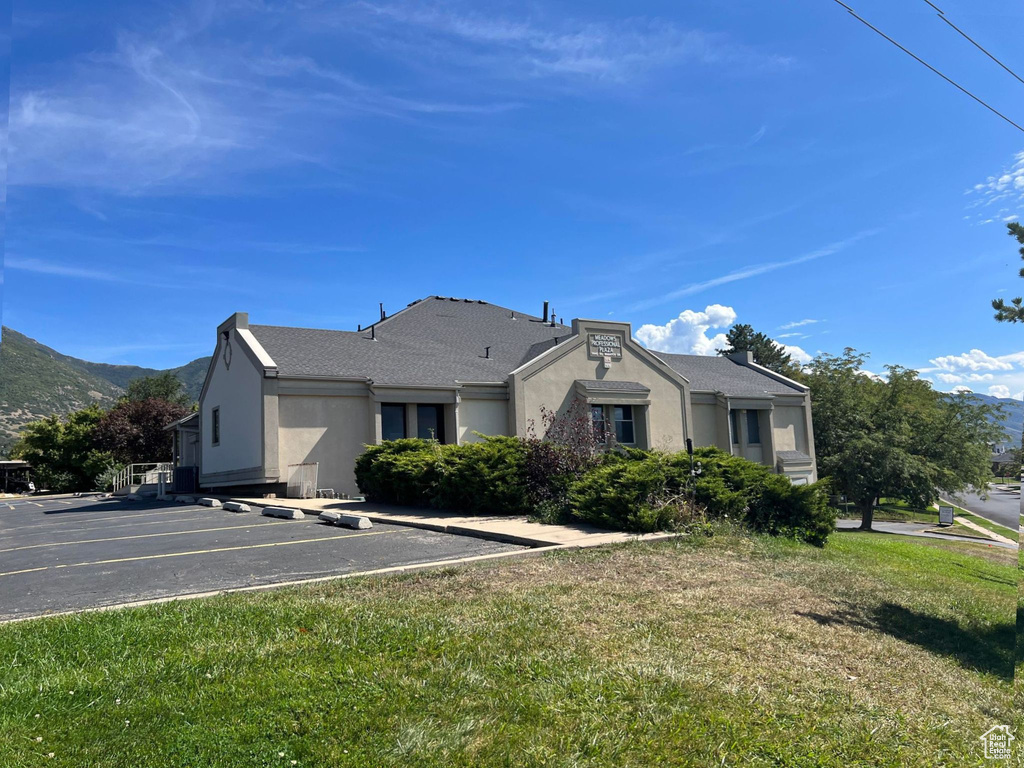 View of front of home with stucco siding, uncovered parking, a front yard, and a mountain view