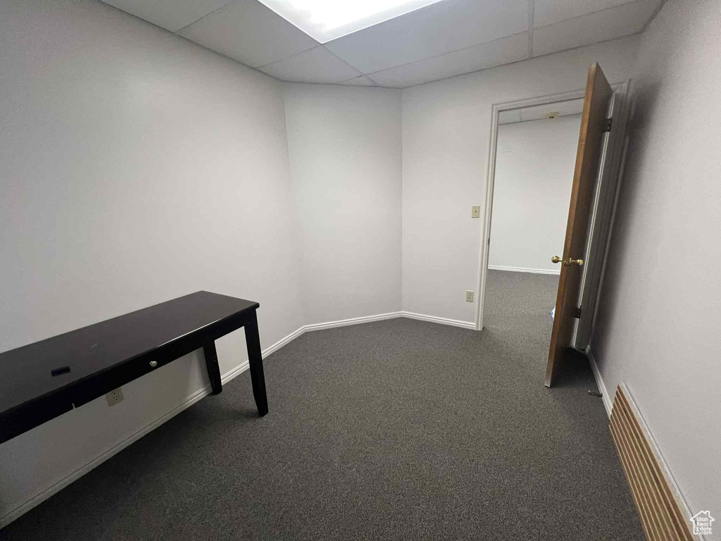 Carpeted empty room featuring a paneled ceiling and baseboards