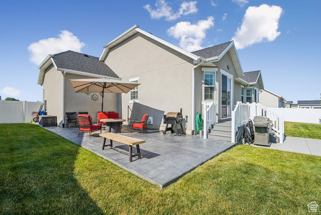 Rear view of property featuring a patio, stucco siding, and roof with shingles