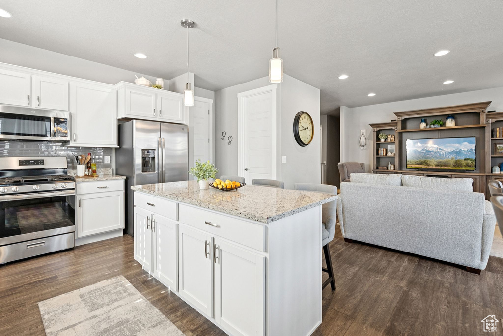 Kitchen featuring stainless steel appliances, recessed lighting, dark wood-style flooring, a kitchen bar, and backsplash