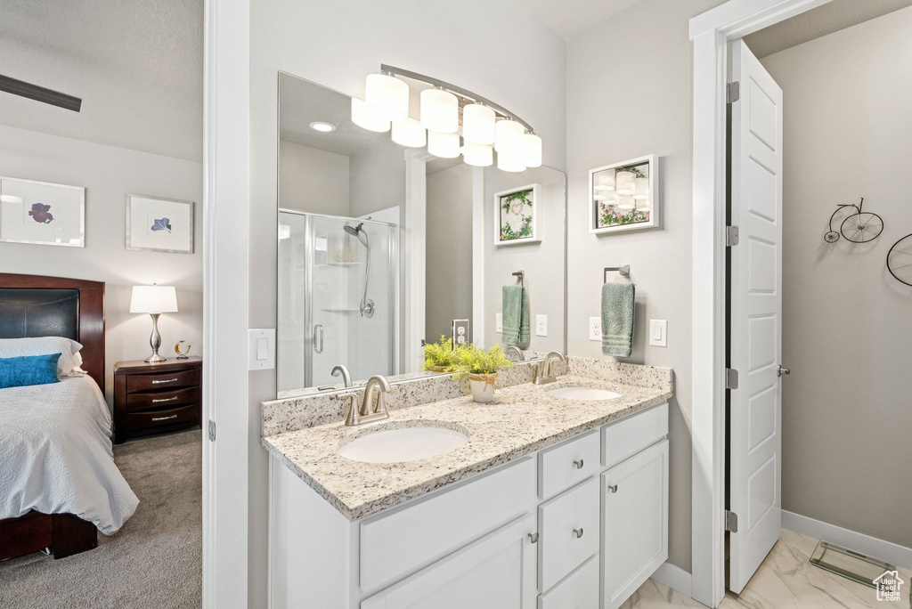 Full bath featuring ensuite bathroom, double vanity, a stall shower, and marble look tiles