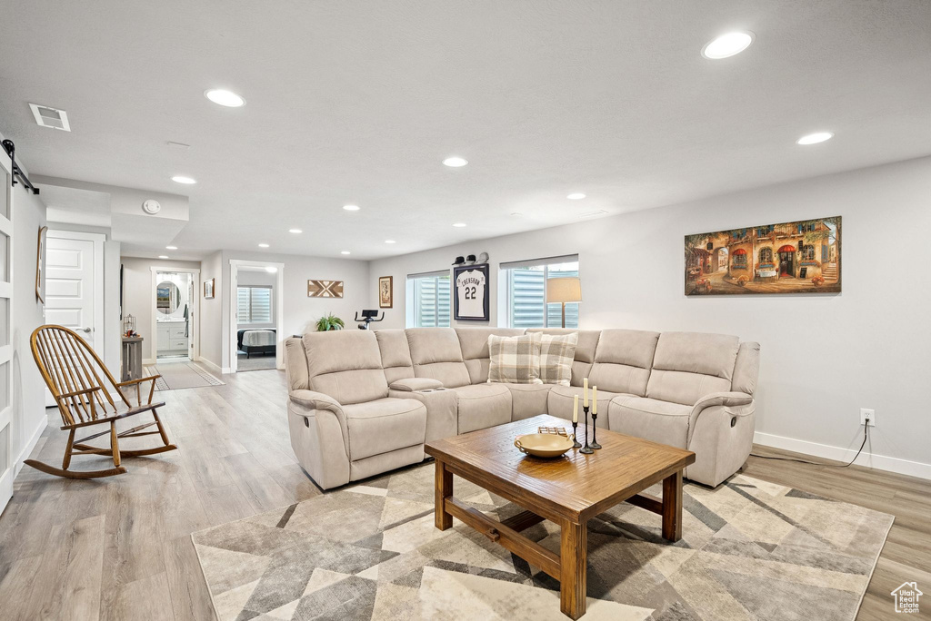 Living room with a barn door, recessed lighting, and light wood-type flooring