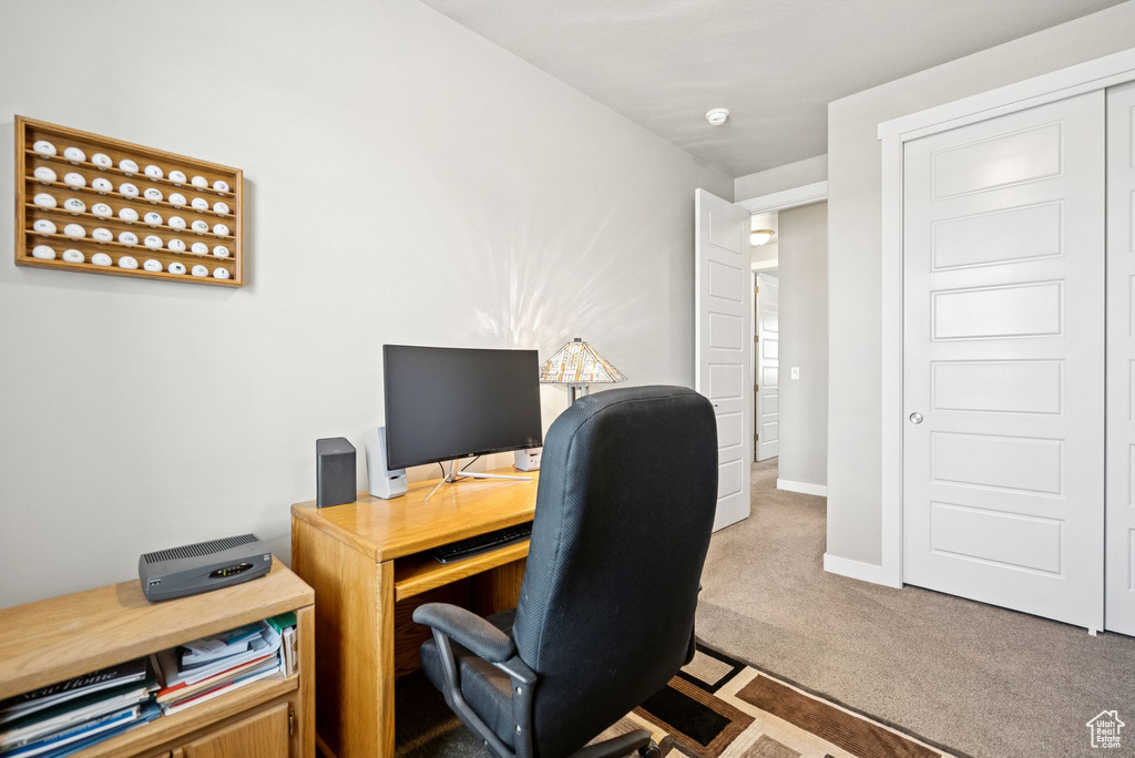 Carpeted home office featuring baseboards