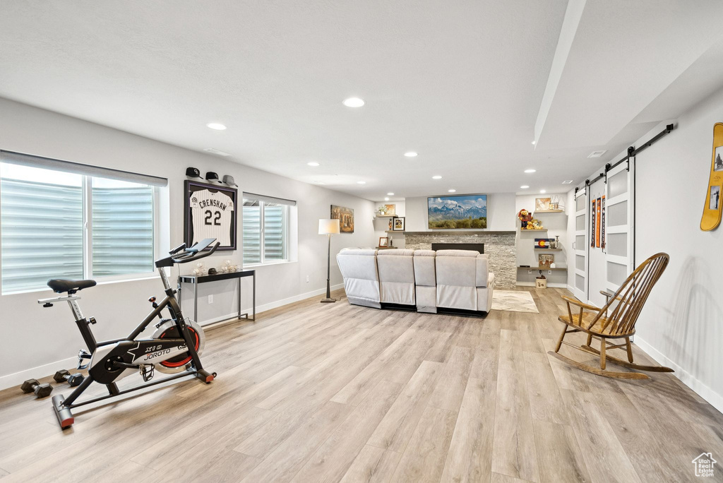 Living room with a barn door, recessed lighting, light wood-style floors, plenty of natural light, and a fireplace