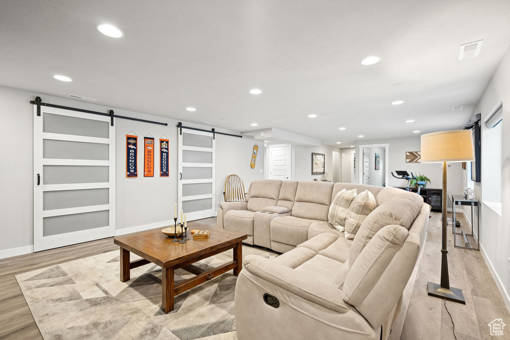 Living area featuring a barn door, recessed lighting, and light wood-style flooring