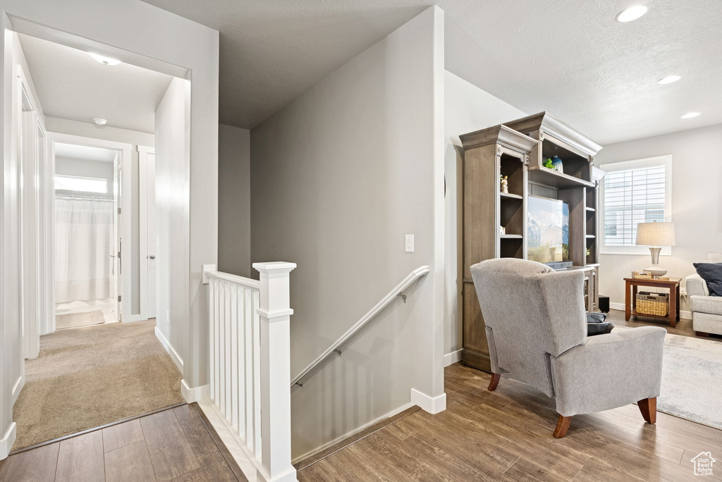Corridor featuring an upstairs landing, wood finished floors, and recessed lighting