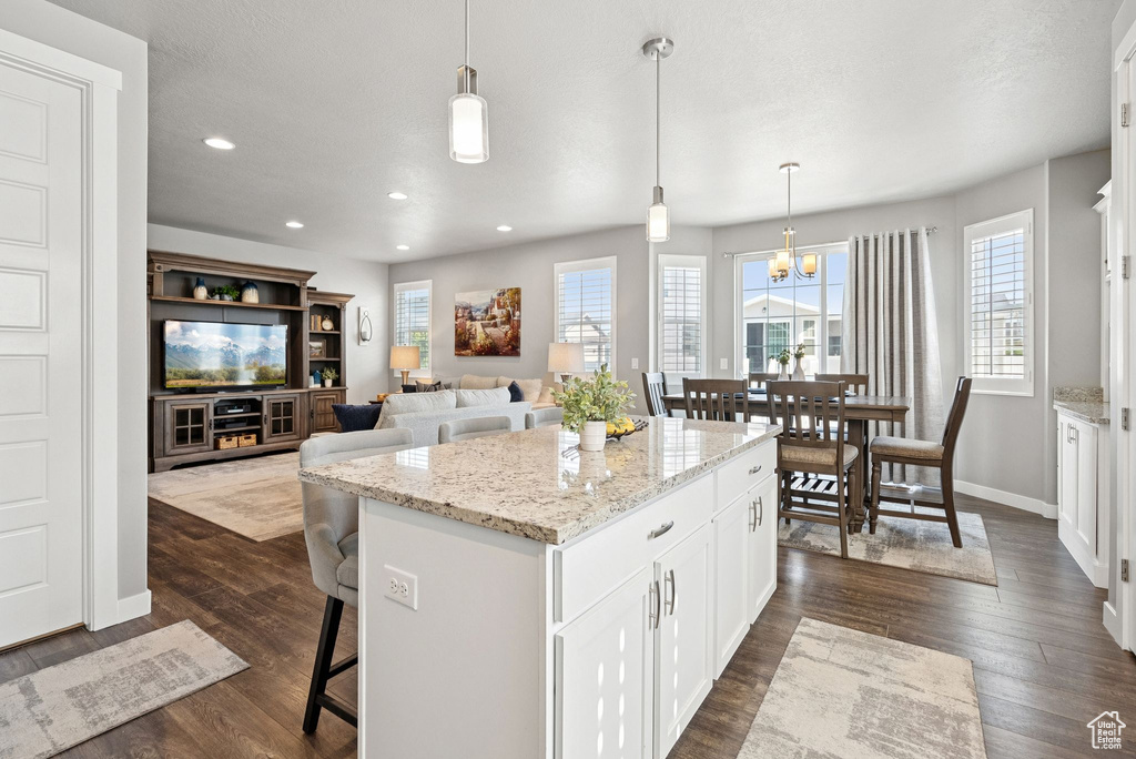 Kitchen featuring plenty of natural light, a kitchen bar, a center island, white cabinets, and recessed lighting