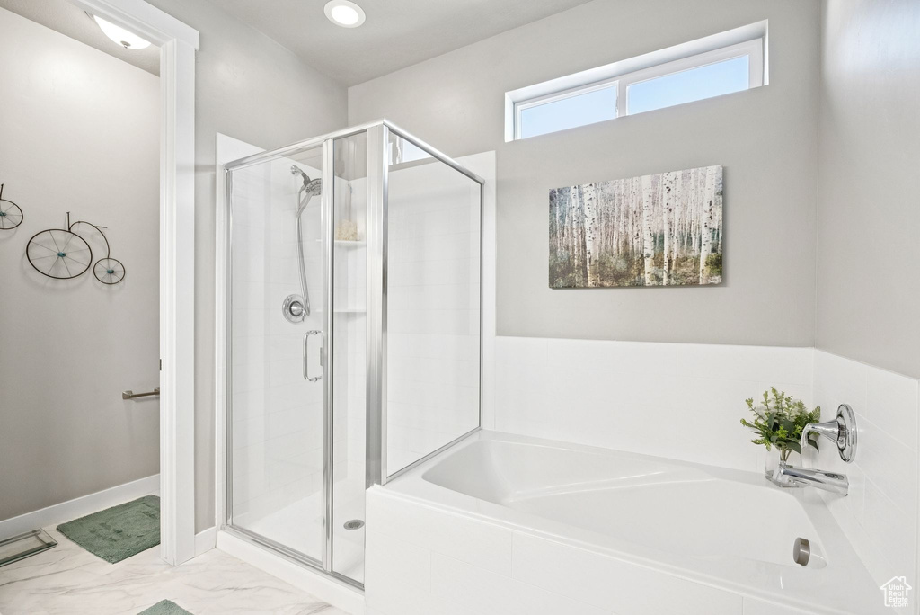 Full bath featuring a garden tub, a stall shower, and marble look tile flooring