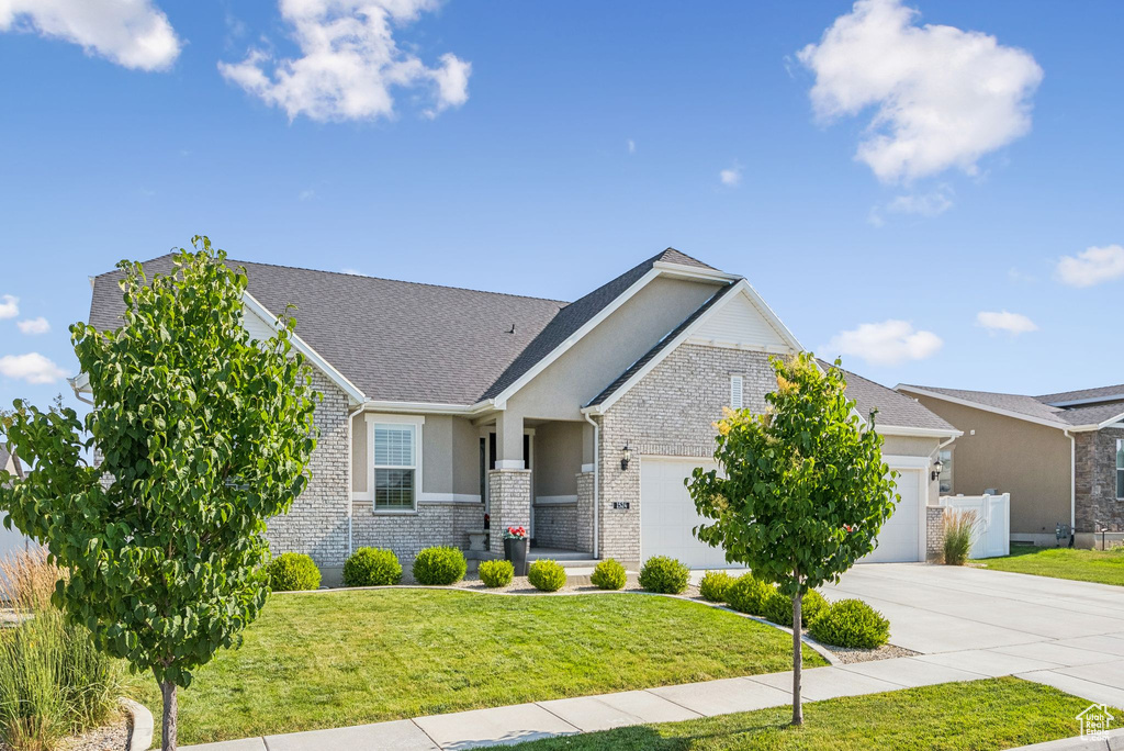View of front of house featuring an attached garage, concrete driveway, brick siding, stucco siding, and a shingled roof