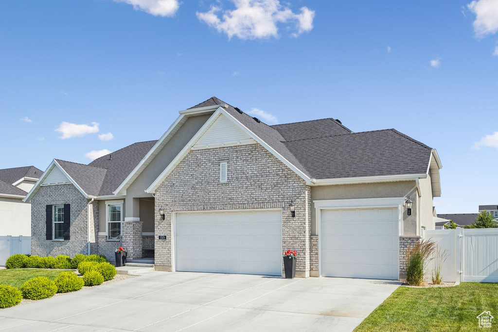 View of front of property featuring an attached garage, concrete driveway, brick siding, and a shingled roof