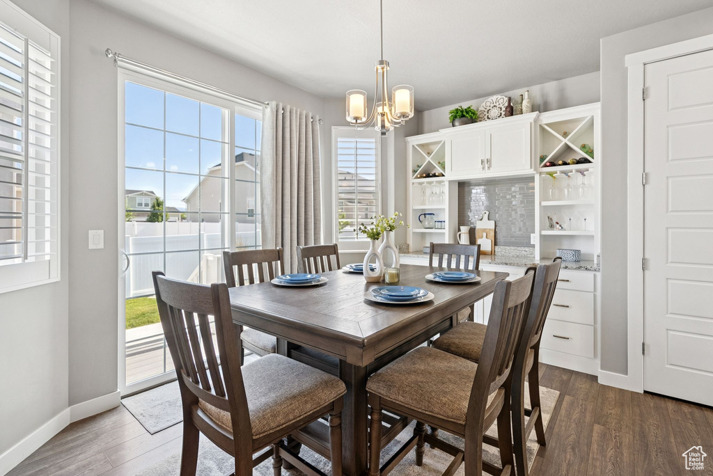 Dining space with a chandelier and dark wood-style flooring